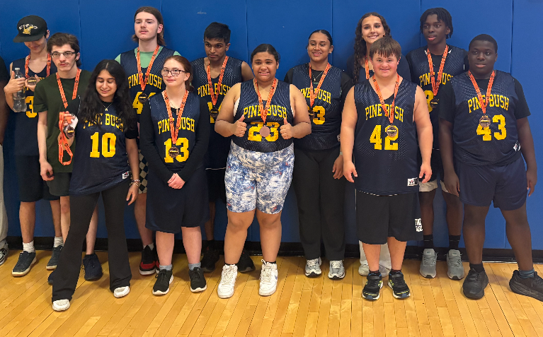 A group of 12 high school students stand together in navy blue basketball uniforms. They have medals around their necks.